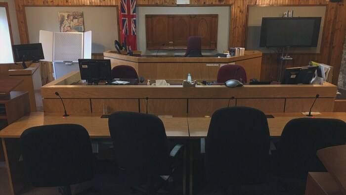 Des chaises vides dans la salle d'audiences avec en arrière-plan le drapeau de la province de l'Ontario.