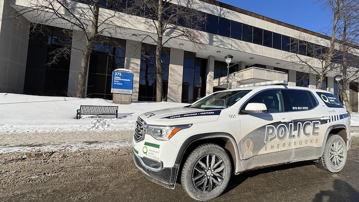 Plan large d'un véhicule de police avec le palais de justice de Sherbrooke en arrière plan.