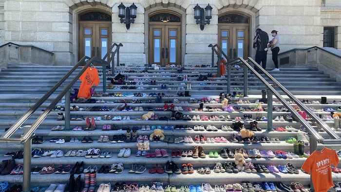 薩斯喀徹溫省里賈納市的省議會大樓前臺階上，人們擺上了215 雙鞋，以悼念在 BC省坎盧普斯市前原住民寄宿學校舊址發現的215 名兒童的遺骸。