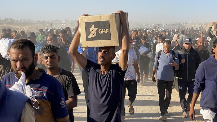 Des milliers de Palestiniens marchent en transportant des boîtes fournies par la Fondation humanitaire de Gaza.