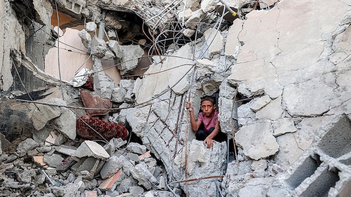 Un garçon sort des décombres d'un bâtiment effondré sous les bombardements.