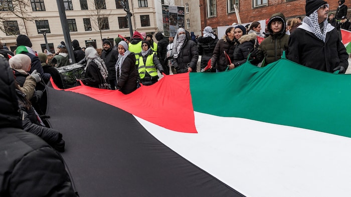 Des personnes tiennent un drapeau.