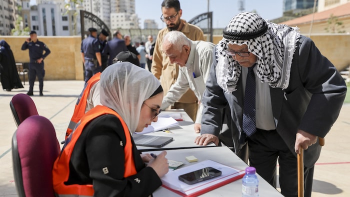 Des électeurs palestiniens font la queue tandis que des agents électoraux vérifient leurs pièces d'identité dans un bureau de vote à Hébron, en Cisjordanie occupée.