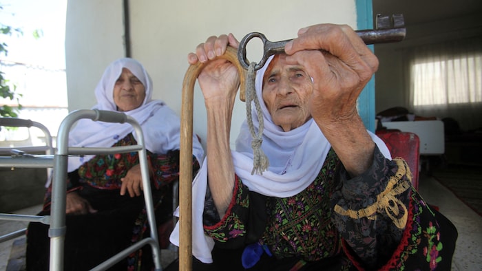 Une aînée palestinienne tient une vieille clé dans sa main.