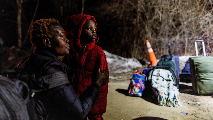 Pamela Haiala, originally from Congo, looks towards Canada with her son as they wait to cross at Roxham Road, an illegal crossing point from New York State to Quebec in Champlain, New York, on March 24, 2023.