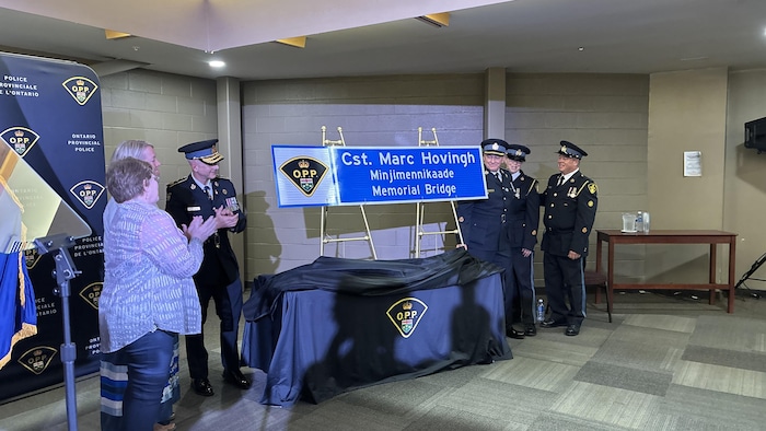 Des policiers devant la pancarte commémorative en l’honneur de l’agent provincial Hovingh.