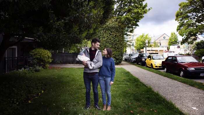 Deux parents se regardent avec leur nouveau-né dans les bras.