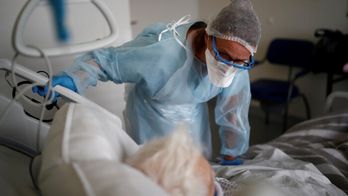 Un médecin se penchant sur le lit d'un patient.