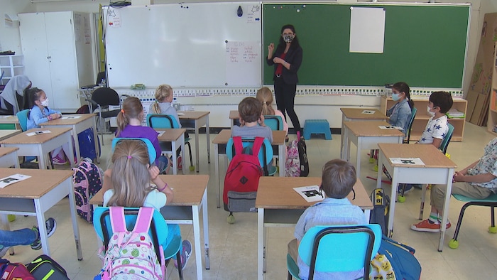 معلّمة تتحدث إلى تلاميذها في قاعة الصف.