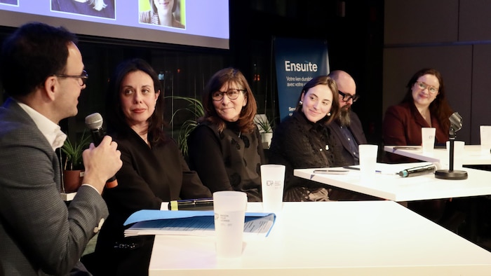 Six personnes assises. L'une d'elles parle au micro. Les autres la regardent.