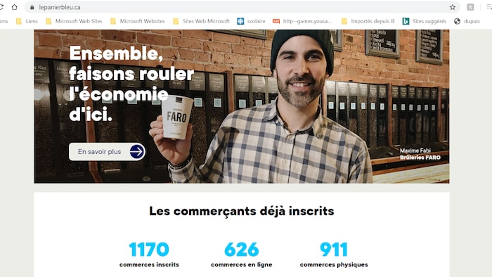 Un homme tient un café dans ses mains et sourit à la caméra.