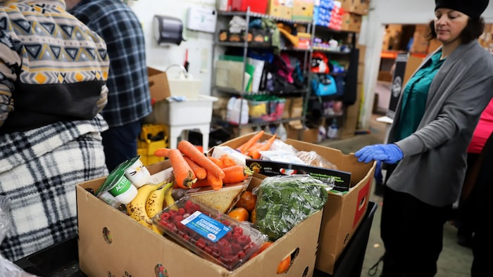 Une personne assemble des paniers alimentaires.