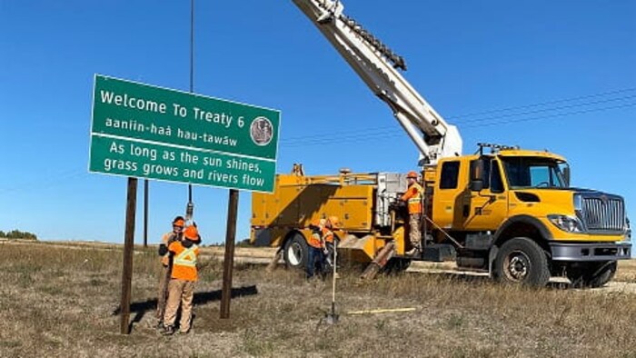 Une équipe installe un panneau de signalisation annonçant aux automobilistes qu'ils entrent sur le territoire du Traité 6 en Saskatchewan.