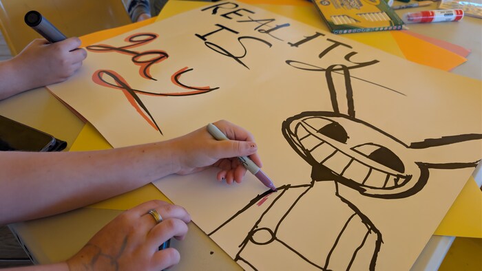 Mains décorant une grande affiche sur une table.