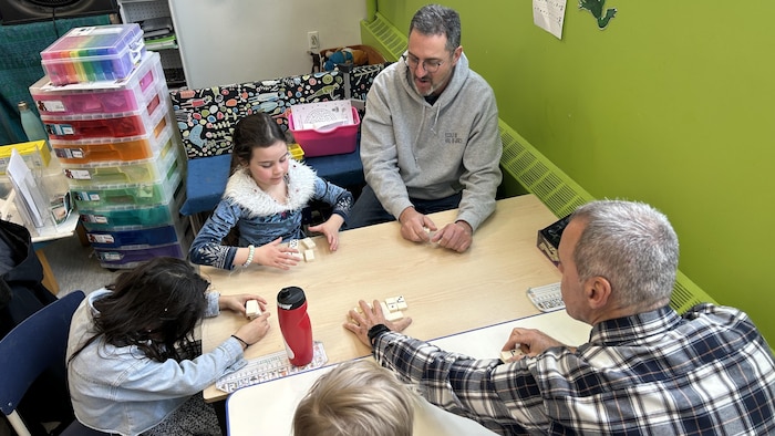 des grands-papas jouent a des jeux de societe dans une classe avec des eleves.