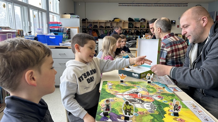 des papas jouent a des jeux de societe en classe.