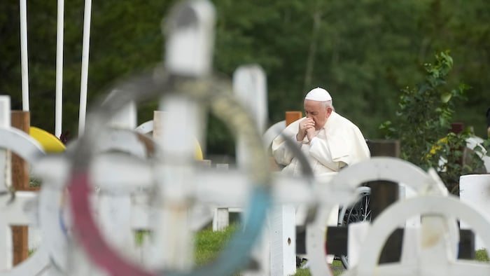 Le pape François, assis dans un fauteuil roulant, se recueille dans un cimetière face à des tombes.