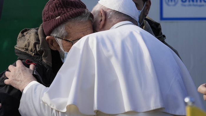 Le pape prend un migrant dans ses bras.