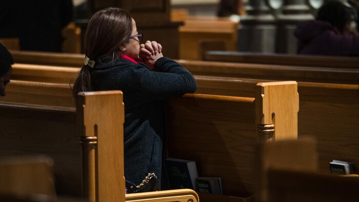 Une femme prie à la cathédrale St. Michael's de Toronto après l'annonce de la mort du pape François.