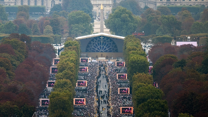 Une foule compacte forme d'épaisses haies d'honneur le long des Champs-Élysées avant la messe solennelle en plein air.