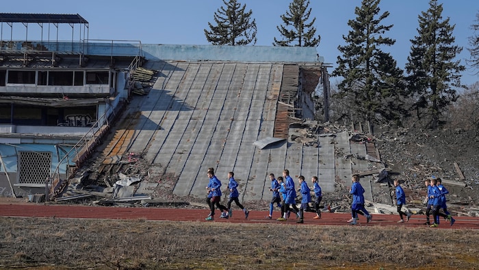 Des jeunes s'entraînent devant le stade endommagé de Chernihiv, en Ukraine. 