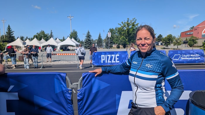 Sylvie Trudel, accotée sur la barrière délimitant la piste, souriante.