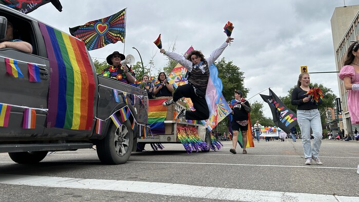 Une personne saute de joie au milieu d'autres gens lors d'un défilé de la Fierté, le 22 juin 2025 à Saskatoon.