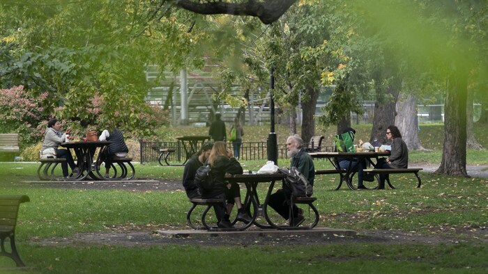 Des gens sont assis à des tables dans un parc.