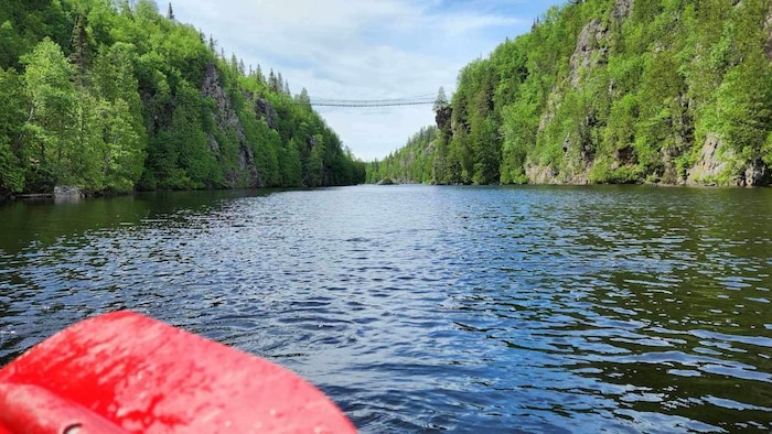 Un canot navigue sur un lac dans le parc d'Aiguebelle et s'approche du pont suspendu.