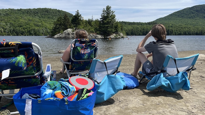 Des vacanciers assis sur la plage du Lac Stukely au parc national du Mont-Orford.