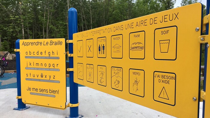 Deux panneaux jaunes, l'un permettant d'apprendre le braille et l'autre permettant aux enfants avec des difficultés langagières de communiquer leurs besoins