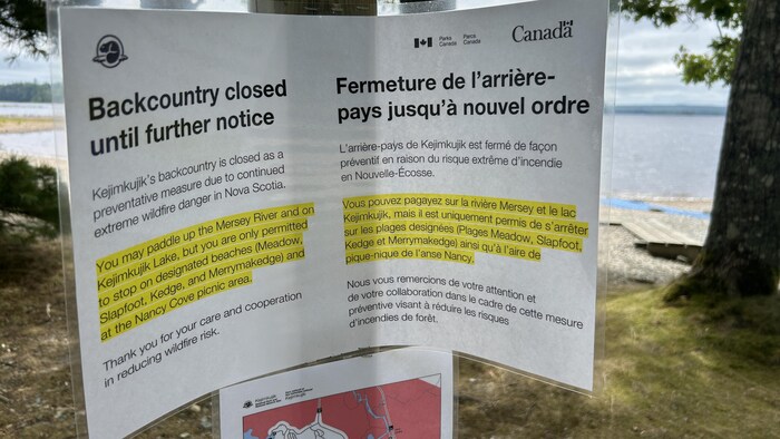 Une feuille plastifiée intitulée «Fermeture de l'arrière-pays jusqu'à nouvel ordre» et marquée du logo de Parcs Canada est clouée à un poteau.