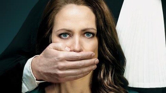 Un homme vêtu d'une toge met sa main sur la bouche d'une femme comme pour l'empêcher de parler.