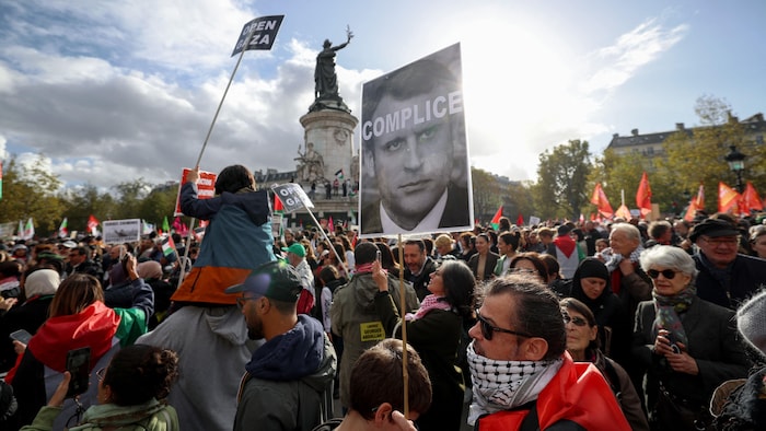 متظاهر يحمل لافتة عليها صورة الرئيس الفرنسي إيمانويل ماكرون مكتوب عليها كلمة ’’متواطئ‘‘ خلال مظاهرة تطالب بالسلام في غزة، ساحة الجمهورية في باريس، 22 أكتوبر، 2023.
