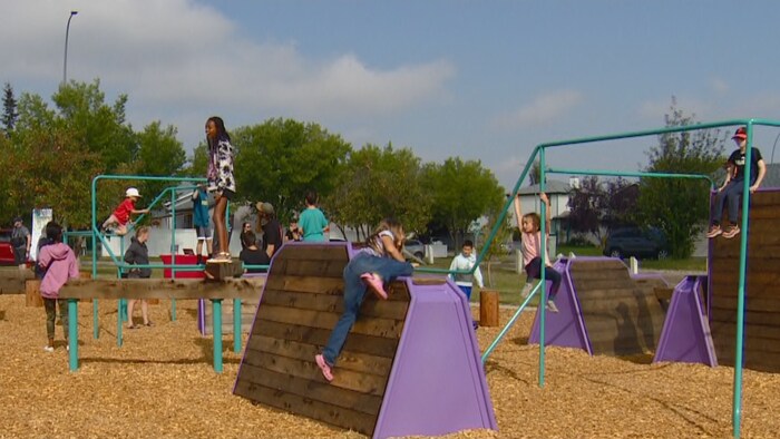 Des enfants en train de grimper sur des structures de jeu dans un parc, à Calgary.