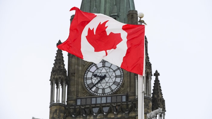 Un drapeau canadien flotte devant la Tour de la Paix du Parlement à Ottawa.
