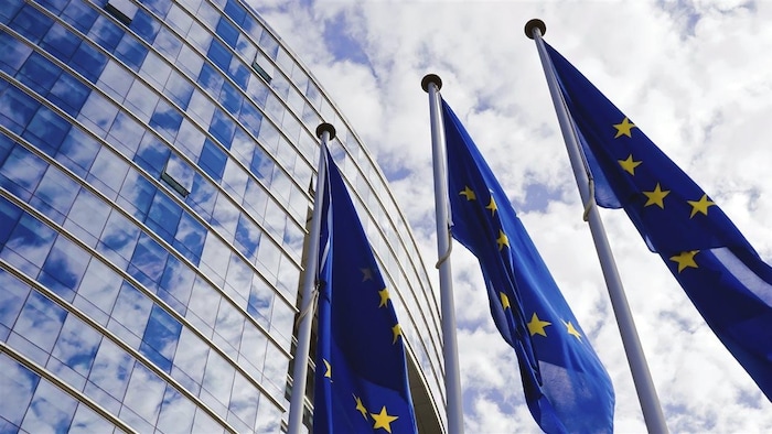 Trois drapeaux de l'Union européenne devant le Parlement européen