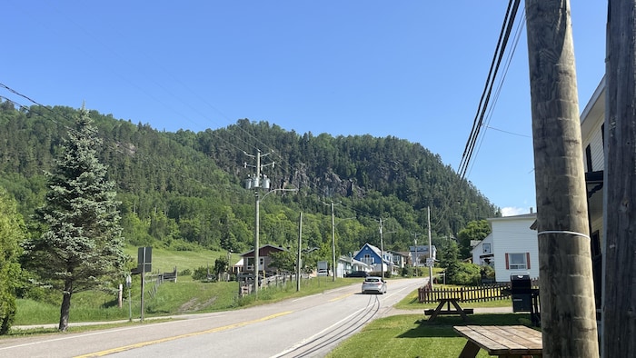 La route principale du village de Sainte-Rose-du-Nord avec une vue sur la paroi d'escalade au loin. 