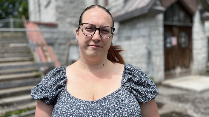 Une personne regarde l'objectif devant un bâtiment.