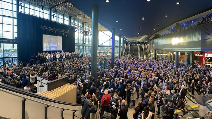 Une foule rassemblée devant une scène dans le hall du Centre Vidéotron.