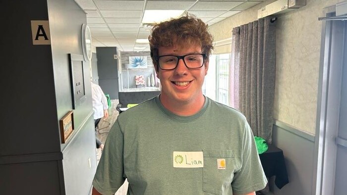 Un jeune homme souriant dans un corridor d'hôtel.