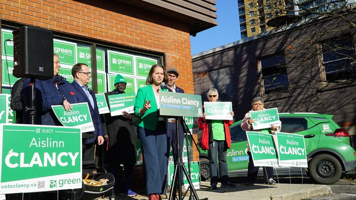 La candidate Aislinn Clancy en campagne, entourée de soutiens et de pancartes.