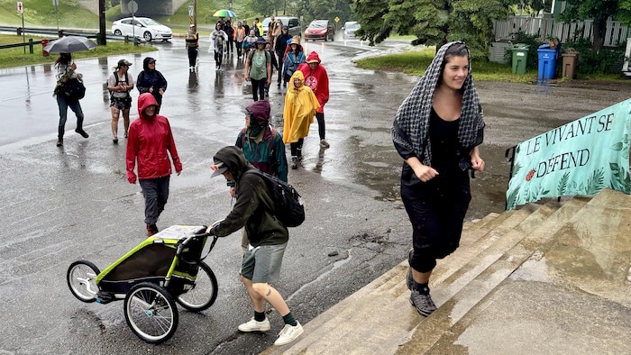 Des marcheurs sous la pluie arrivent sur le perron d'une église.