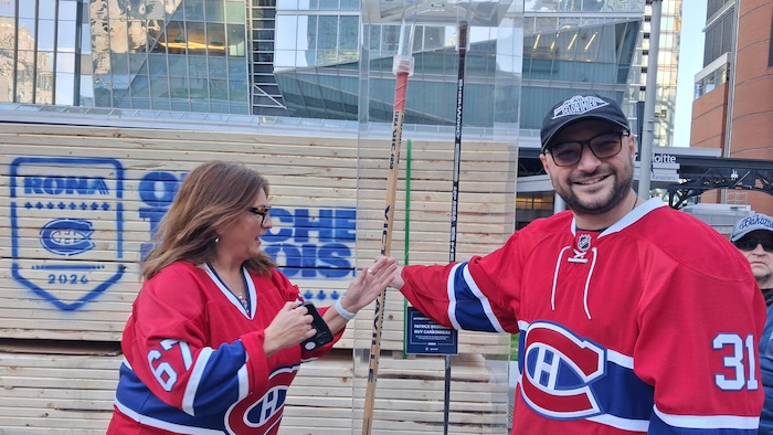 Deux partisans du Canadien devant un bâton de hockey en bois.
