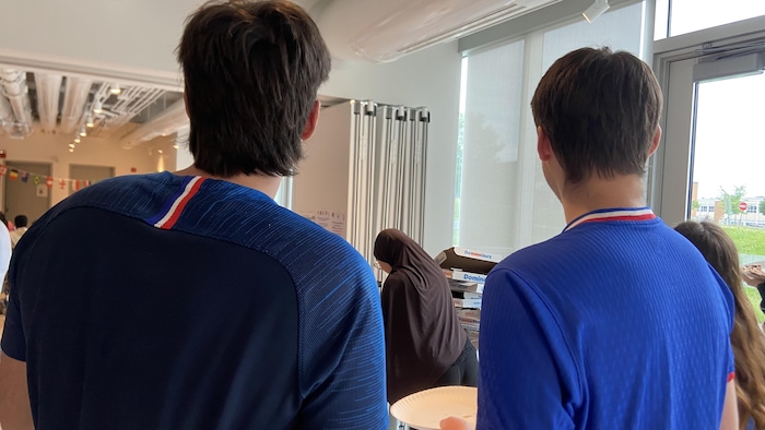 Des étudiants arborant un chandail des Bleus regardent le match France contre Irak.