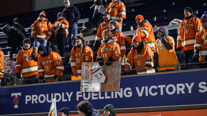 Des gens portant un chandail des Patriotes de l’UQTR sont debout dans des gradins.