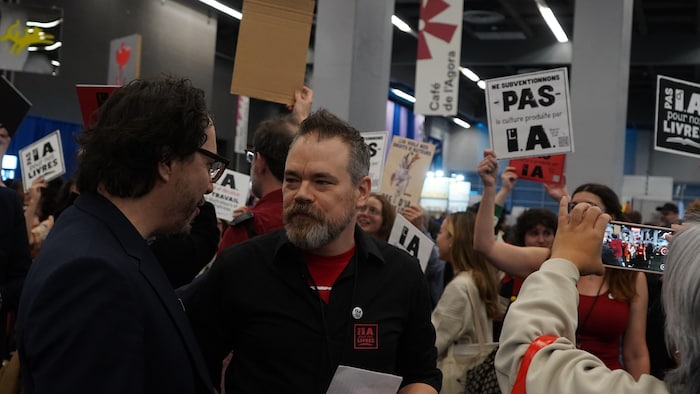 Un homme entourant de manifestants qui tiennent des pancartes.