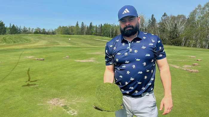 Pascal Gagnon tient un morceau de gazon arraché d'un terrain de golf.