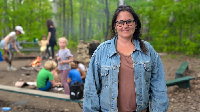 Pascale Demers devant des enfants qui font des activités dans un boisé.