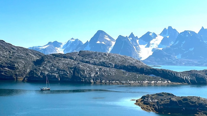 Des roches et des hautes montagnes entourent une mer.
